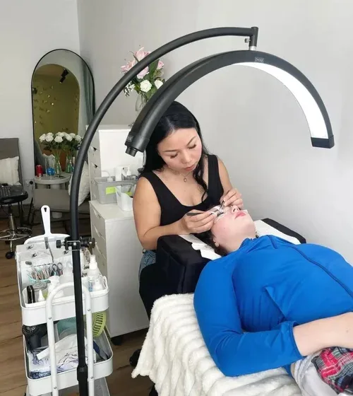 Cherry applying lash treatment under the studio ring light