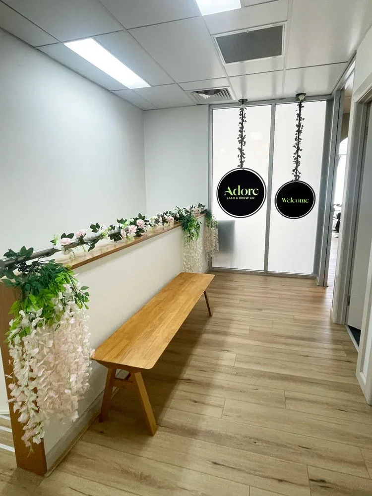 The upstairs entry at Adore — timber bench, faux pink roses, wisteria, and the frosted-glass Adore and Welcome doors